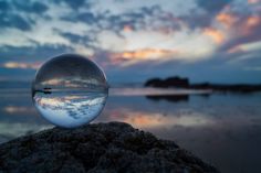 a glass ball sitting on top of a rock near the ocean