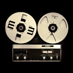 two reels sitting next to each other in front of a radio receiver on a black background