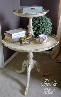 a white table with books on it and a plant in the corner next to it