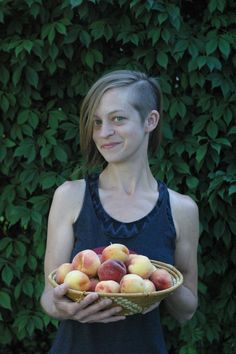 a woman holding a basket full of peaches