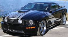 a black mustang parked in front of a body of water