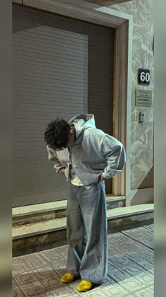 a man standing in front of a door with his hands on his hips while covering his face