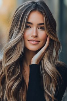 Woman with long wavy hair smiling and touching her face. Light Highlights In Dark Hair, Winter Blonde Highlights Brunettes, Balayage Winter Brunettes, From Dark Hair To Light Hair, Brunet With Highlights, Dark Hair And Highlights Brunettes, Hair Color Ideas For Brunettes Olive Skin, Dark Chocolate Hair With Blonde Highlights, Blonde On Natural Brunette