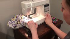 a woman is using a sewing machine to sew something on the side of a table