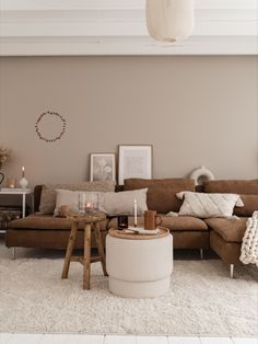 a living room with a brown couch and white rugs on the floor next to a coffee table