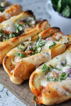 several hot dogs with toppings are lined up on a table