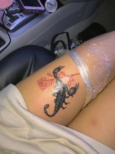 a woman with a scorpion tattoo on her thigh sitting in the back seat of a car