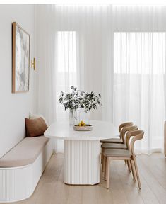 a white dining room table with four chairs and a bench in front of the window