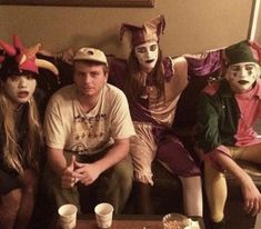 four people dressed up as clowns sitting on a couch with cups and plates in front of them