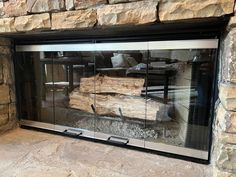 a fire place that has some logs in the glass door and rocks on the wall