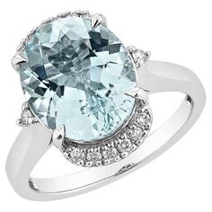 an oval blue topaz ring with diamonds on the shoulders and sides, set in 18k white gold