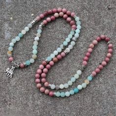 Amazonite Is A Soothing Stone. Wear It And You Will Immediately Feel A Sense Of Inner Peace And Balance. It Possesses A Powerful Energy, Like The River Of Which It Bears The Name, But It Is Nevertheless Capable Of Taming And Calming Negativity And Anger. Rhodonite Helps To Balance The Emotions And Calm Impatience. Rhodonite Is A Very Supportive Stone That Works With The Heart Chakra To Attract Love And Ground Negative Energies. Physically, Rhodonite Is Believed To Support Detoxification And Heal Pink 8mm Beaded Necklace, Pink Necklaces With 8mm Beads, Beaded Rose Quartz Crystal Necklace, Handmade Rose Quartz Beaded Necklace With Round Beads, Pink Natural Stones Beads As Gift, Bohemian Rose Quartz Beaded Necklaces, Pink Beaded Necklaces With Natural Stones, Multicolor Rose Quartz Round Bead Jewelry, Bohemian Rose Quartz Gemstone Beaded Necklace