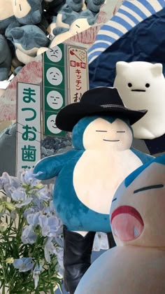 two stuffed animals are sitting next to each other in front of blue flowers and signs