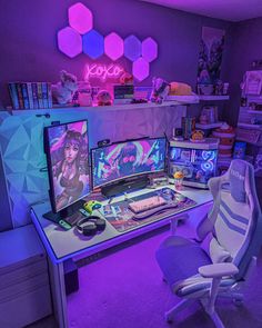 two computer monitors sitting on top of a desk in front of a neon sign above them