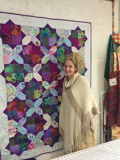 a woman standing next to a large quilt