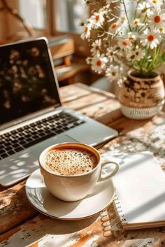 a cup of coffee sitting on top of a saucer next to a laptop computer