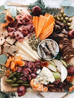 an assortment of cheeses, meats and vegetables on a platter with olives