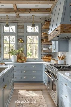 a kitchen with blue cabinets and white counter tops, wooden beams in the ceiling and an area rug on the floor