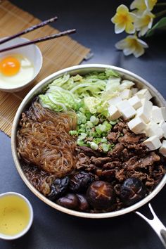 a bowl filled with meat and vegetables next to eggs