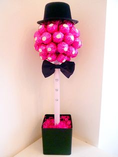 a black hat and bow tie on top of a pink candy tree in a box