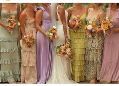 a group of women standing next to each other wearing dresses and holding bouquets in their hands