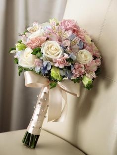 a bridal bouquet sitting on top of a white chair