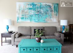 a living room filled with furniture and a large painting on the wall above it's coffee table