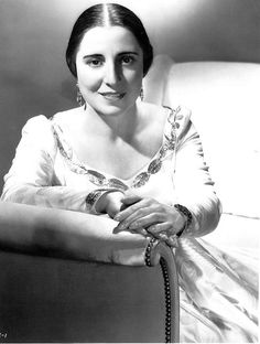 an old black and white photo of a woman sitting in a chair with her arms crossed