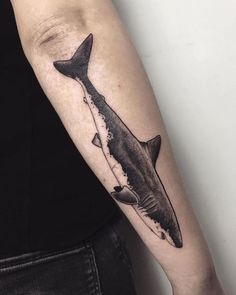 a black and white photo of a shark tattoo on the right arm, with an inking effect