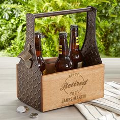 a wooden crate with six beer bottles in it on top of a table next to some napkins