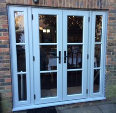 a white double door with glass panels on the side of a brick wall and patio area