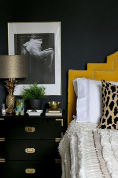 a black and white bedroom with yellow headboard, leopard print throw pillow, gold accents