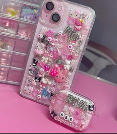 hello kitty phone case with lots of charms on the front and back sides, sitting next to each other