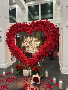 a heart shaped display with roses and candles in front of it that says will you marry me?