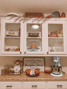 a kitchen with white cabinets and pumpkins on the counter