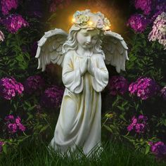 an angel statue in the middle of some purple and white flowers with lights on its head