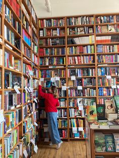 a person standing in front of a bookshelf filled with lots of different colored books