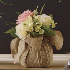 a vase filled with flowers sitting on top of a wooden table covered in burlock