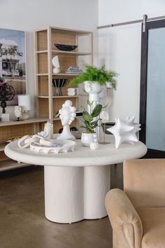 a living room filled with lots of furniture and flowers on top of a white table