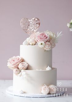 a white wedding cake with pink flowers and hearts on top