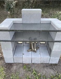 an outdoor fire pit made out of concrete blocks and steel grates, with logs sticking out of it