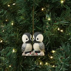 an ornament in the shape of two penguins on a christmas tree with lights