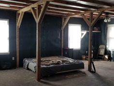 a bed sitting in the middle of a room under wooden beams on top of it