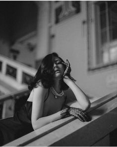 a black and white photo of a woman sitting on a bench with her hands to her face