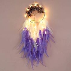 a purple and white dream catcher hanging from a wall with lights on it's sides