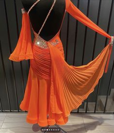 an orange ballroom dress on display in a store window with beads hanging from it's back