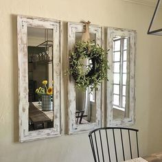 three mirrors hanging on the wall above a dining room table with a wreath and sunflowers