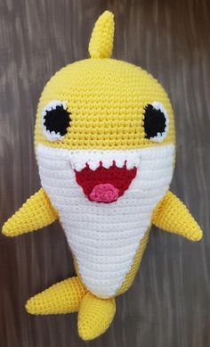 a crocheted yellow stuffed animal with black eyes and mouth is smiling at the camera