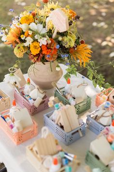 a table topped with lots of small baskets filled with different types of flowers and marshmallows