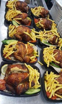 several trays filled with chicken and french fries on top of a metal countertop